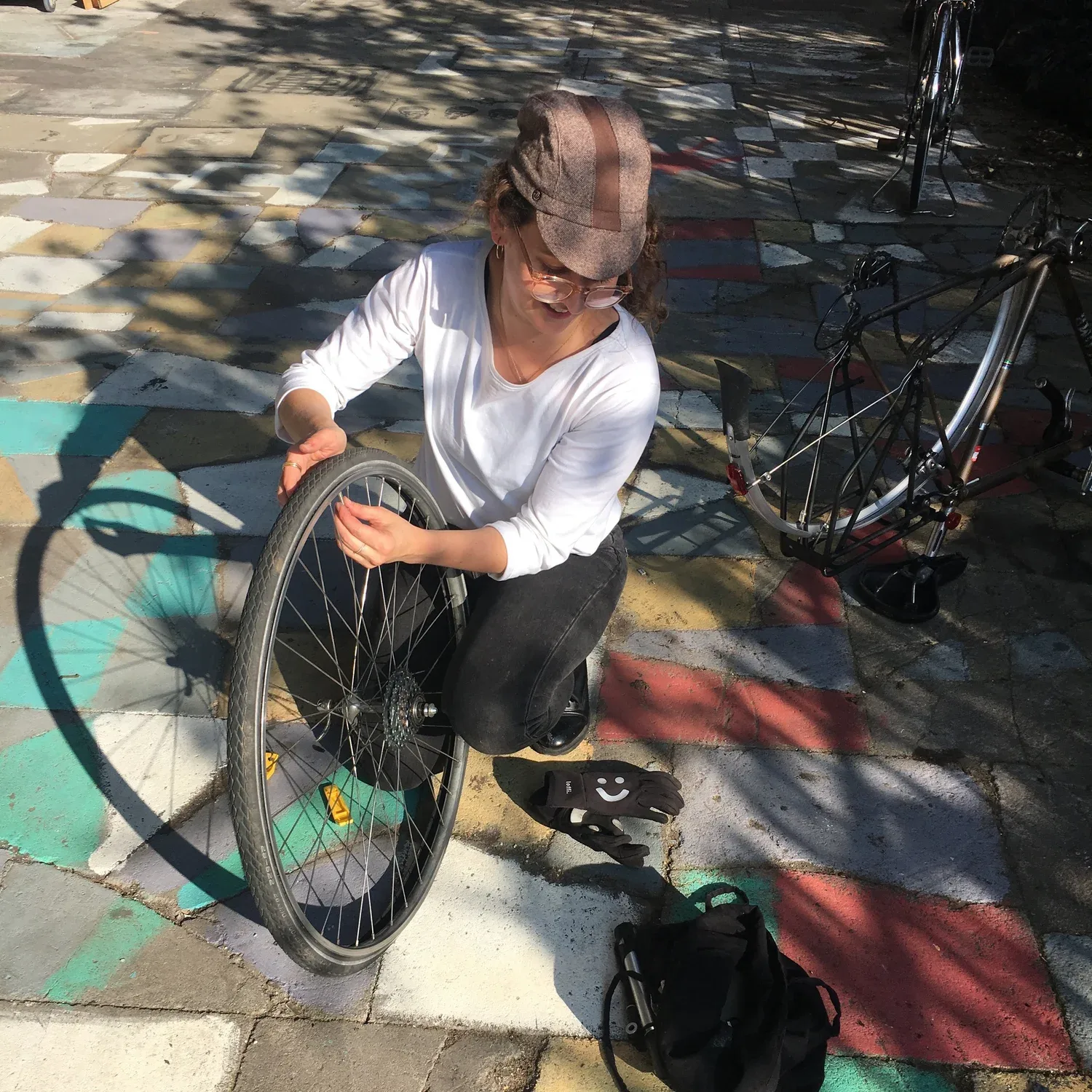 A rider fixing a wheel on the street outside the shop